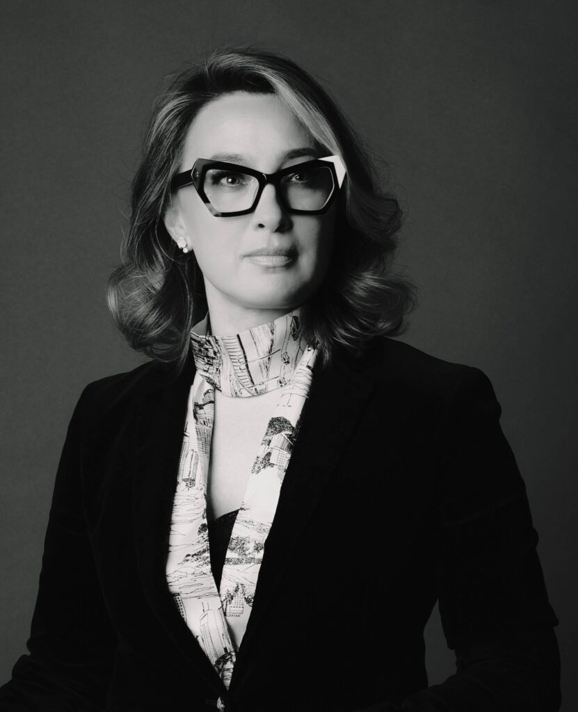 Black and white business portrait of a professional woman in bold glasses and velvet blazer, Brussels