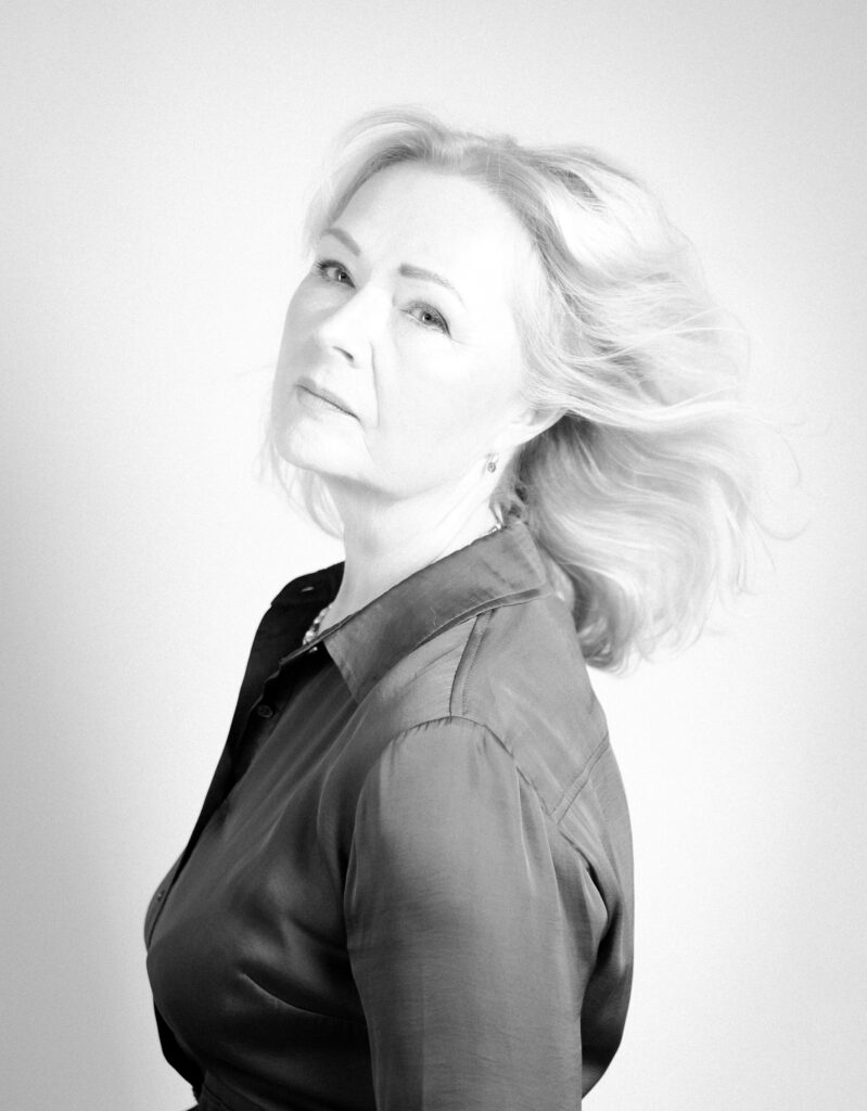 Black and white portrait of a mature woman looking over her shoulder, windswept hair, high-key studio light