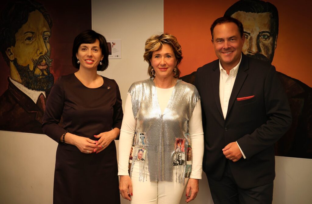 Event photographer in Brussels – three guests posing at an art exhibition in front of large painted portraits